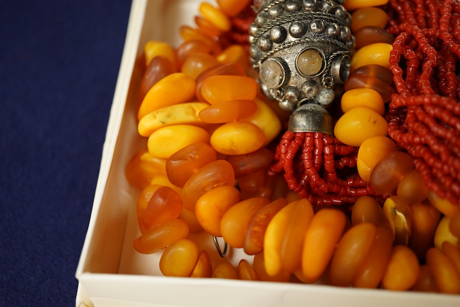 Two necklaces, comprising: a multi-strand coral necklace of torsade design, spaced by beads set with various hardstones, length 73cm; and an amber bead necklace, length 57cm